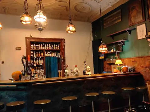 Bar — Drewniany bar, stołki, mosiężne lampy i półki pełne butelek. Zamawiasz przy barze.