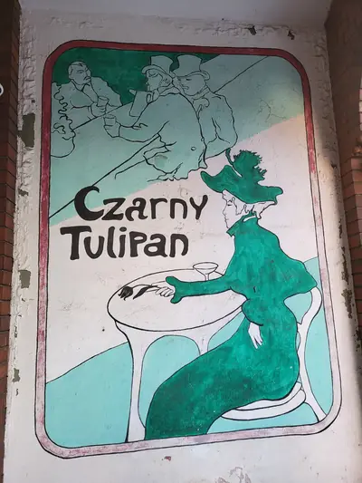 Mural z napisem „Czarny Tulipan”: secesyjna dama w zielonej sukni przy stoliku