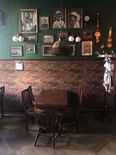 Ściana z obrazami — Butelkowa zieleń, cegła, stare fotografie i obrazy w złotych ramach.